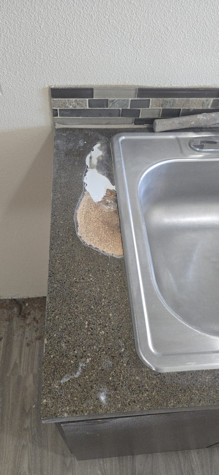 Kitchen sink and countertop before resurfacing, with chipped and peeling laminate