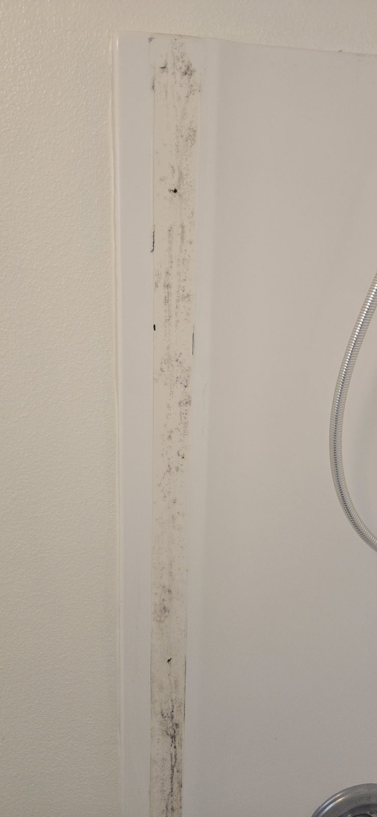 Bathtub ledge before resurfacing, with built-up grime and staining along the rim