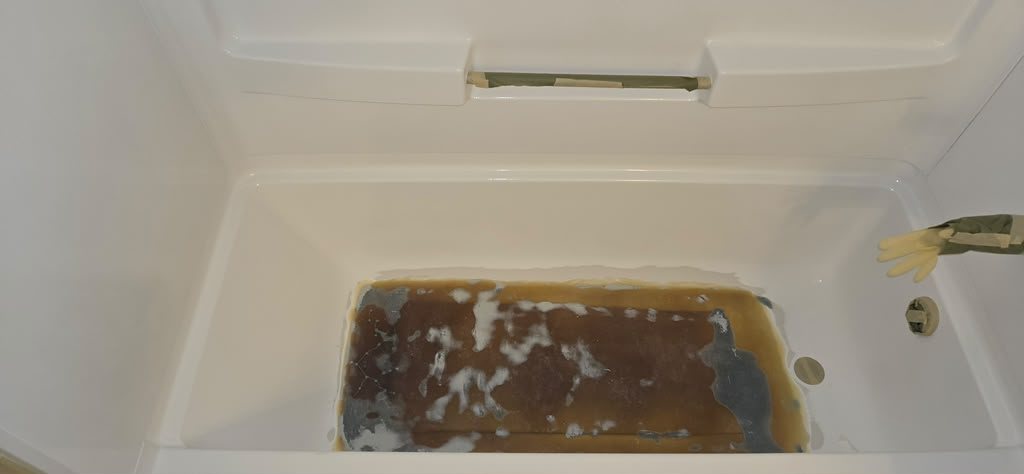 Bathtub interior before resurfacing, with heavy staining across the floor of the tub